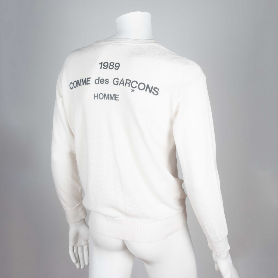Comme des Garçons Homme 1989, a white long sleeve knit shirt with brand text on back.